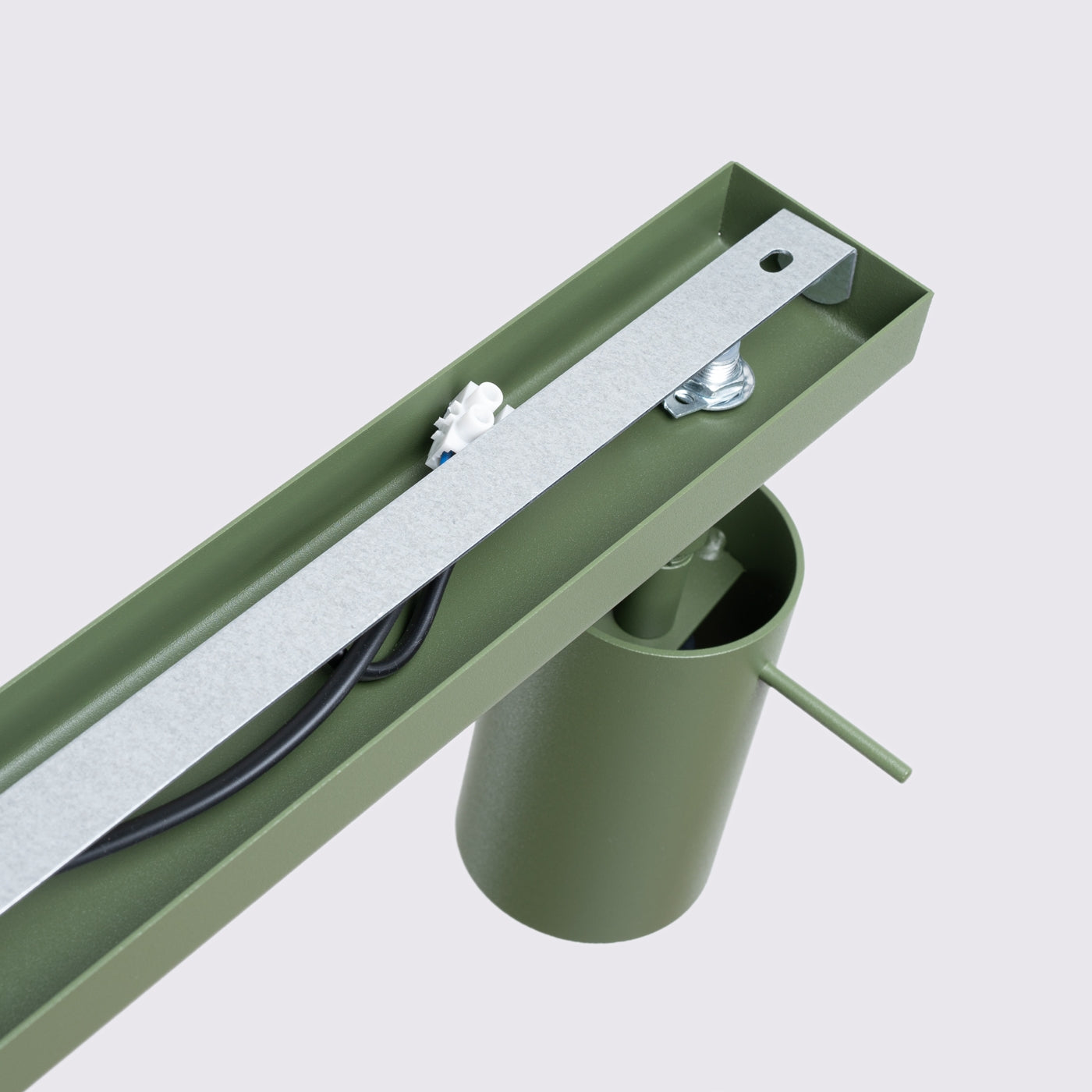 Nahaufnahme eines metallisch grünen Geräteelements mit Silberstreifen, schwarzem Kabel und weißem Stecker.