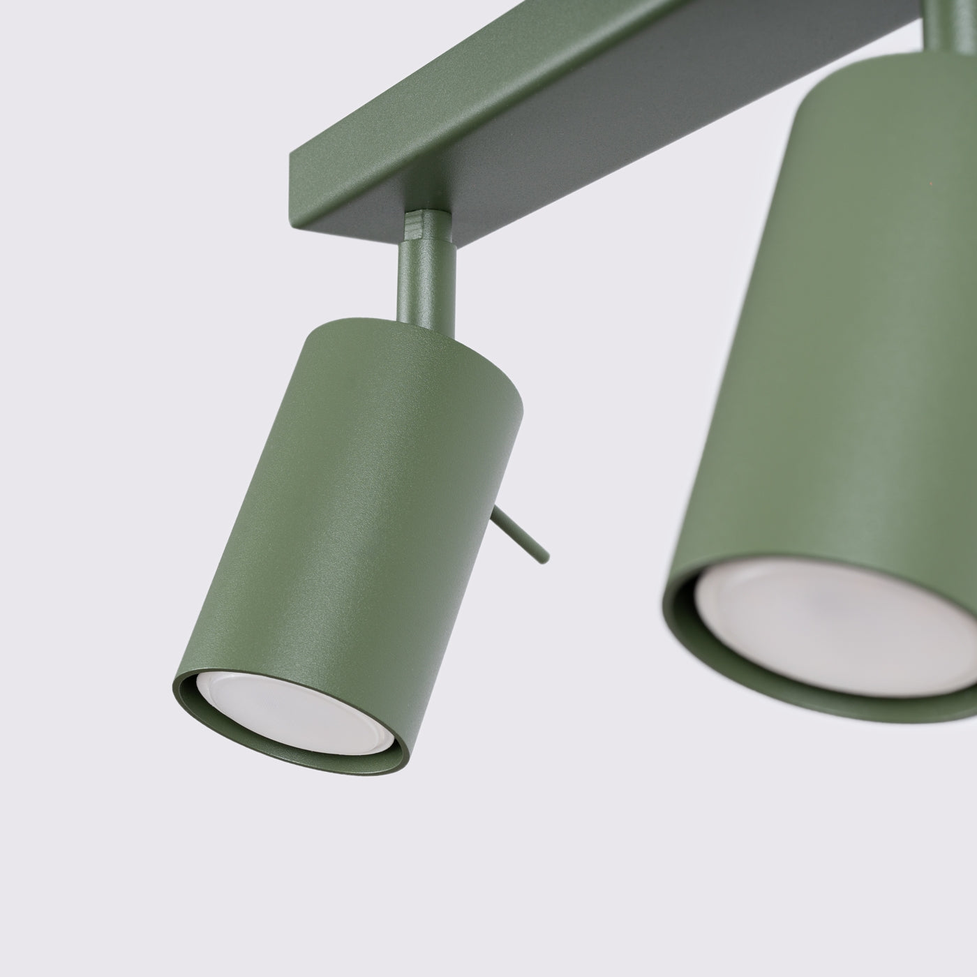 Zwei matte grüne zylindrische Strahler an rechteckigem grünen Montagebalken für minimalistisches Lichtdesign.