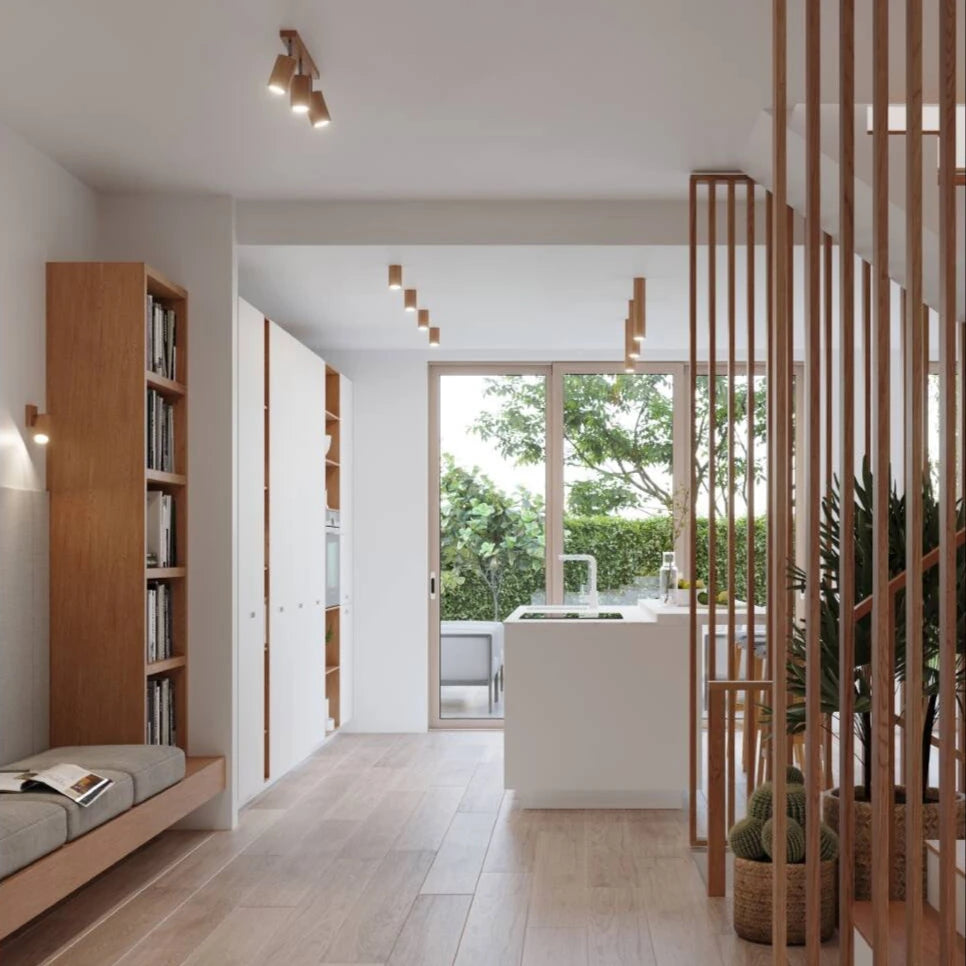 Helle, moderne Wohnküche mit Holzdetails, integrierter Sitzbank, Bücherregal und Blick in den Garten durch große Glastüren.