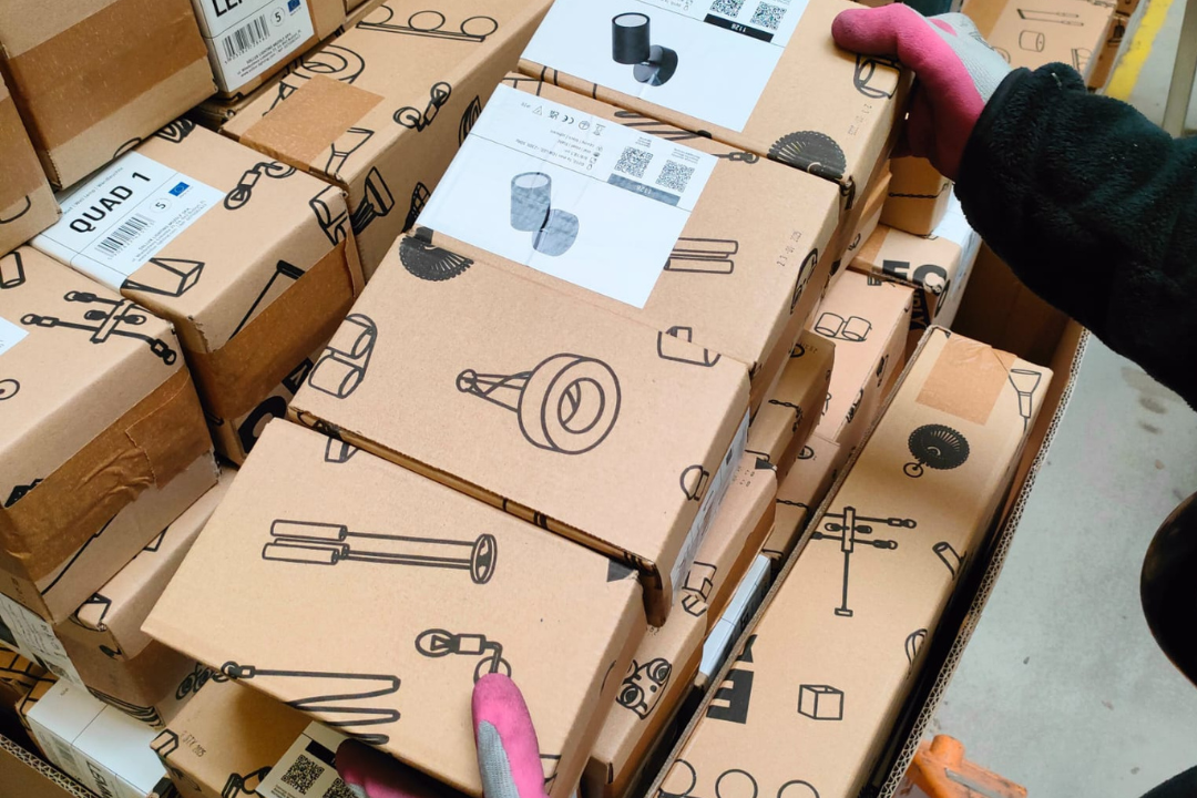 Gestapelte SOLLUX Kartons mit illustriertem Design und nachhaltigem Papierklebeband beim Verpackungsprozess.