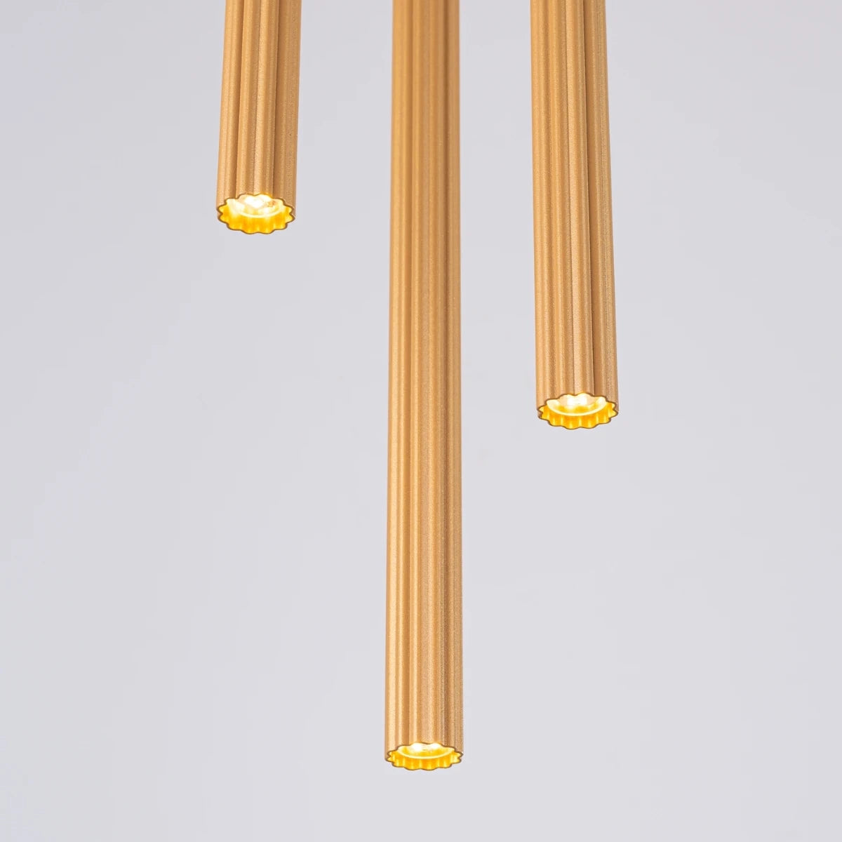 Pendelleuchte CORA 3P in Gold – elegante Ansicht der leuchtenden Zylinder mit geriffeltem Design und warmem Licht