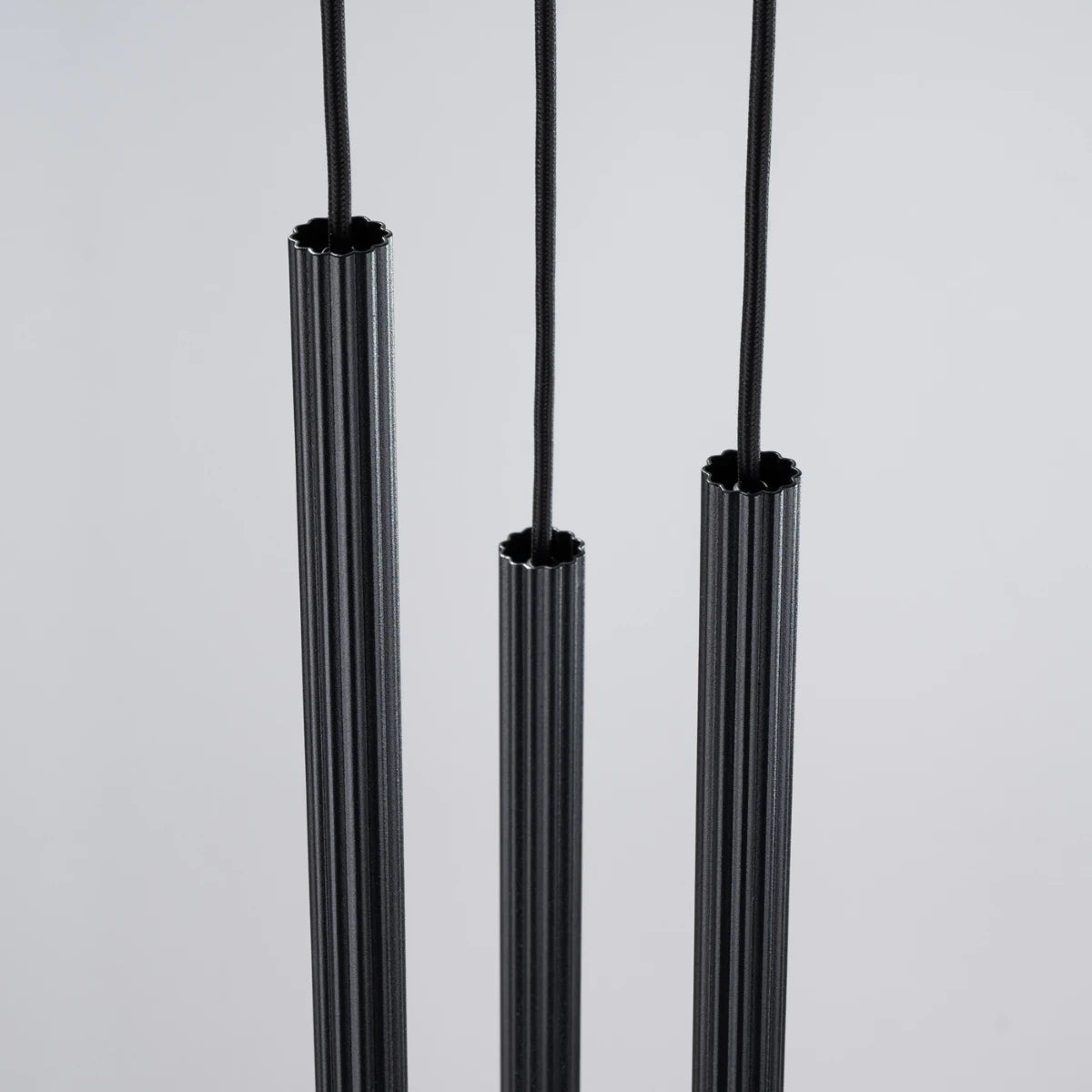 Pendelleuchte CORA 3P in Schwarz – Nahaufnahme der feinen Rillenstruktur mit Kabeldetail und hochwertigem Metallfinish