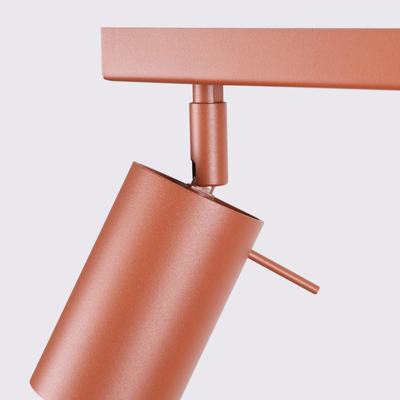 Zylindrische Strahlerleuchte mit rostfarbener Mattierung an horizontaler Schiene im minimalistischen Design