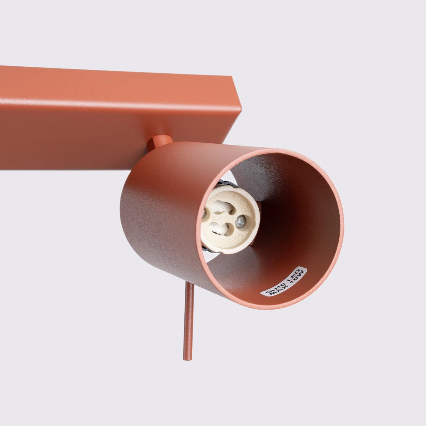 Rostfarbener Spotlight-Strahler mit GU10-Fassung vor grauem Hintergrund