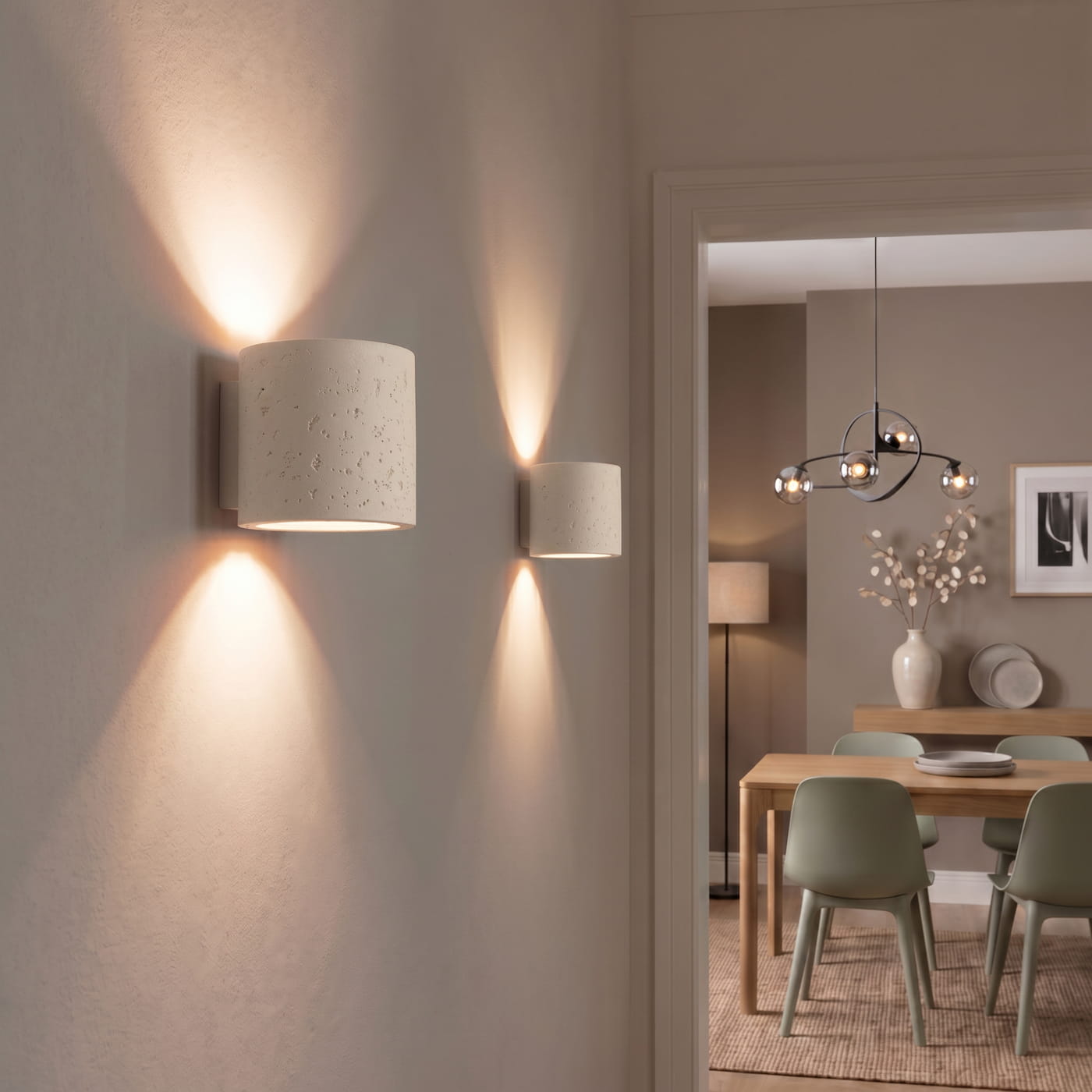 Zwei weiße ORBIS Wandleuchten aus Beton mit warmem Up- und Downlight im modernen Wohn- und Essbereich