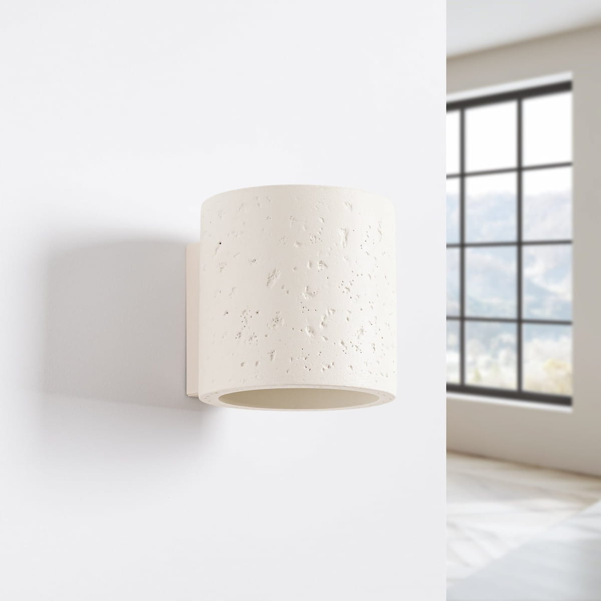 Weiße ORBIS Wandleuchte aus Beton an heller Wand mit modernem Raumhintergrund