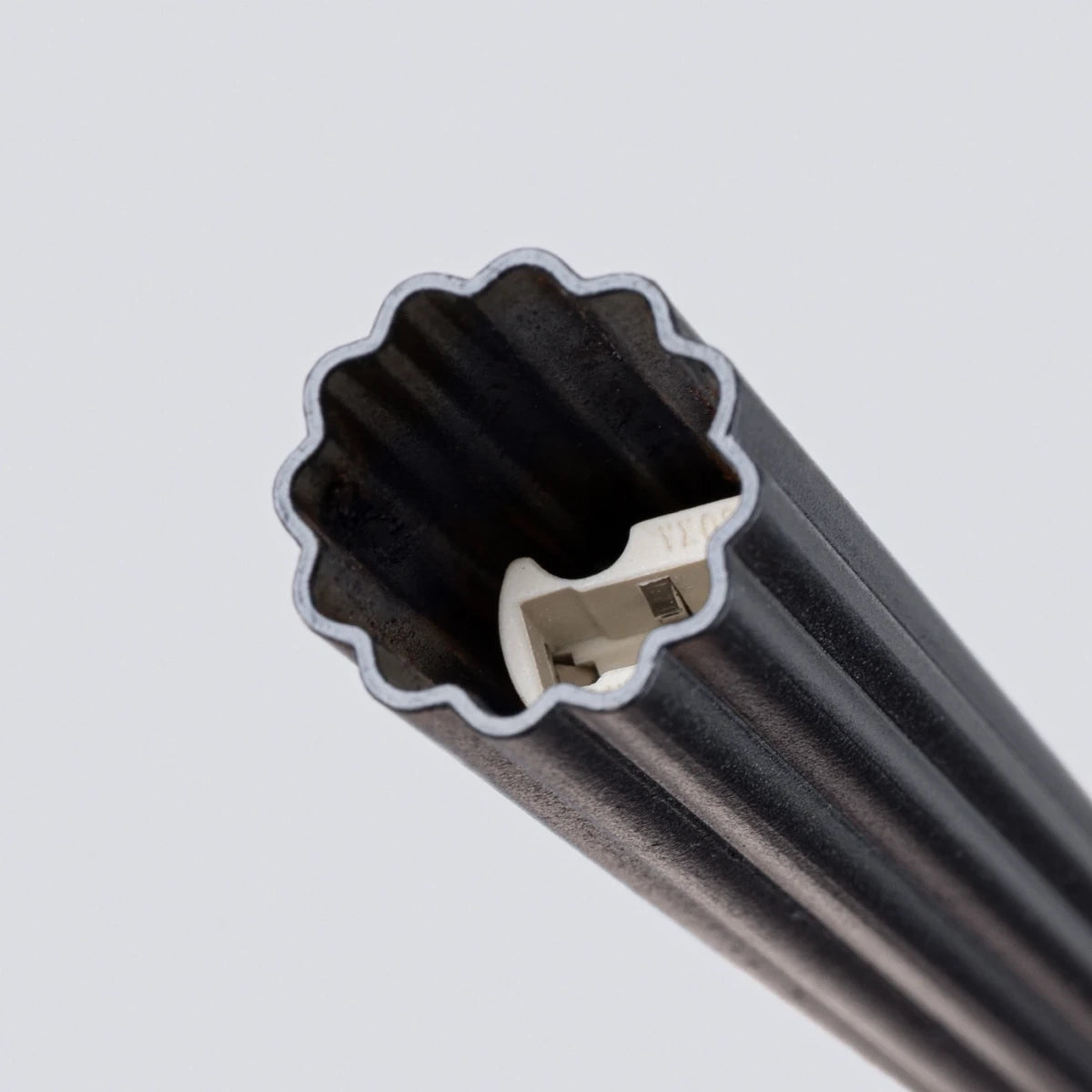 Makroaufnahme der Pendelleuchte CORA 1 in Schwarz – feine Aluminiumrillen und sichtbare Leuchtfassung im modernen Zylinderdesign.