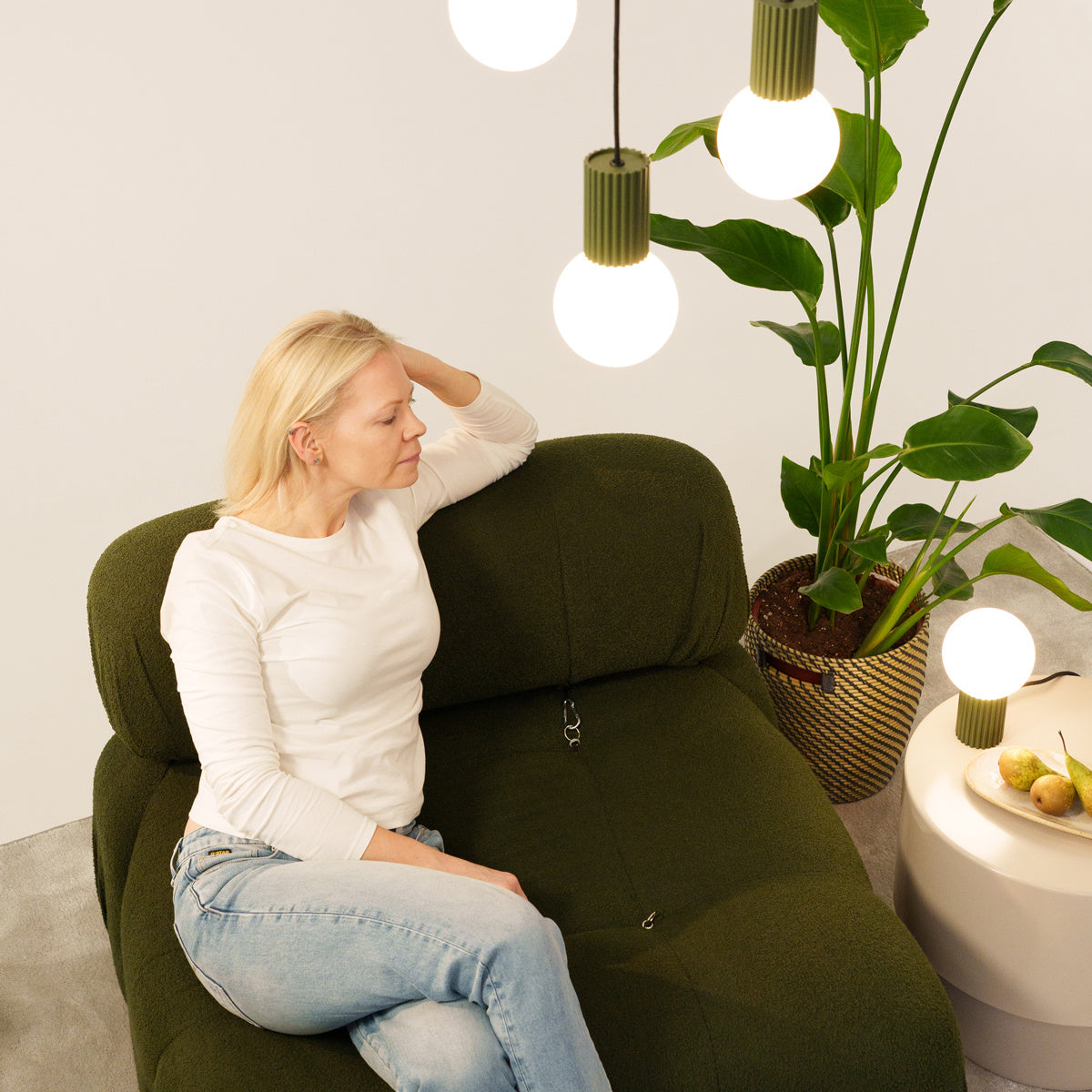 Design-Szene mit HALO-Tischlampe in Olivgrün und drei passenden Pendelleuchten, modernes Interieur mit Pflanze.