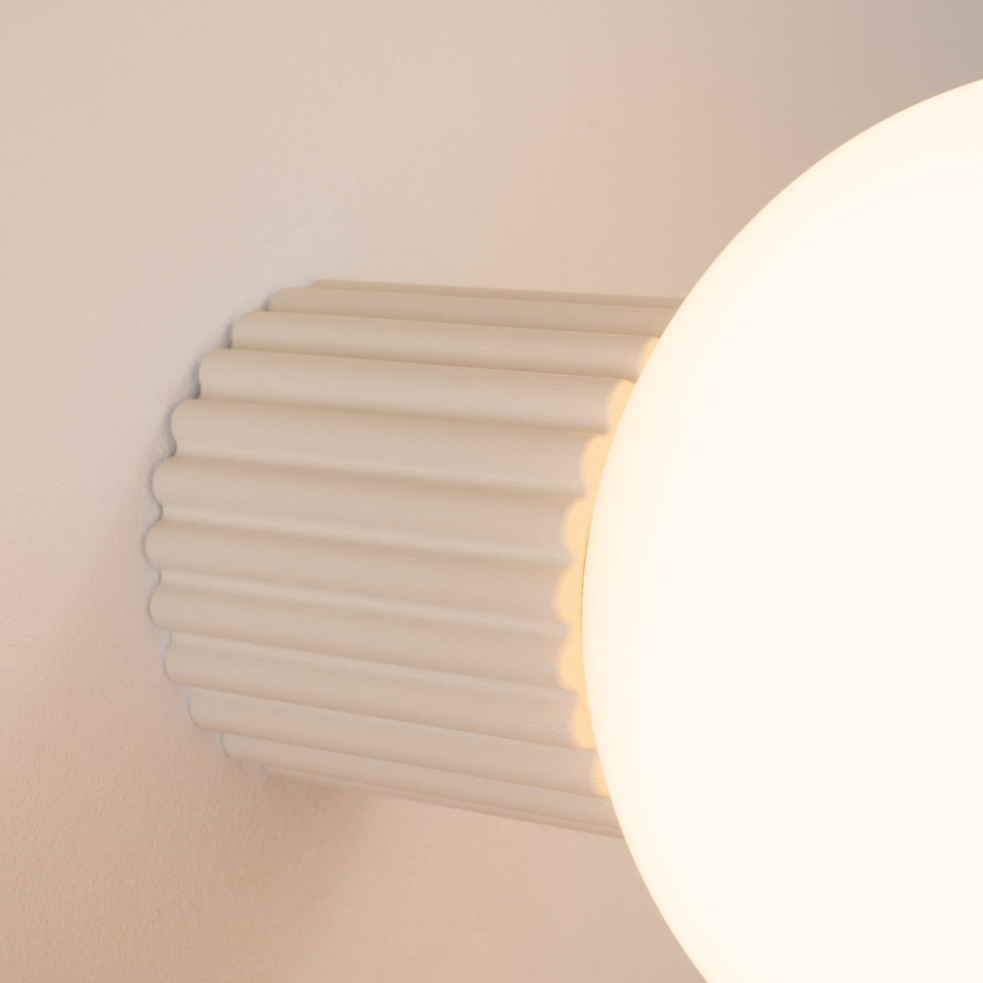 Detailansicht der HALO-Wandleuchte IP44 in Beige, strukturierte Fassung mit opaler Glaskugel.